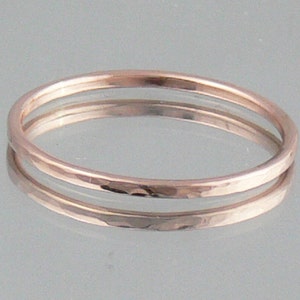 May include: Two thin, hammered rose gold rings stacked on top of each other. The rings are simple and delicate.