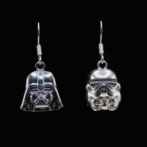 May include: A pair of silver-colored dangle earrings. One earring features a detailed Darth Vader helmet, and the other showcases a Stormtrooper helmet. Both earrings have a hook and coiled wire design for attachment.