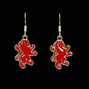 May include: A pair of gold earrings with red lion charms. The lions are in a heraldic pose with their tails curled.