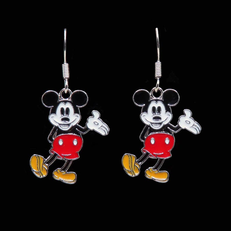 May include: A pair of silver-toned dangle earrings featuring the iconic Mickey Mouse character. Each earring showcases Mickey in his classic outfit: red shorts, yellow shoes, and white gloves, with a black background.