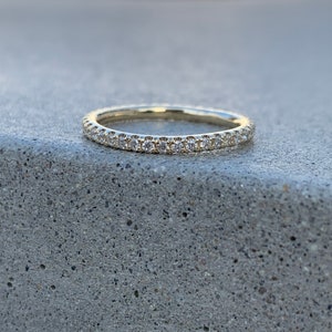 Può includere: Una sottile fascia d'oro con una fila di piccoli diamanti incastonati a pavé.