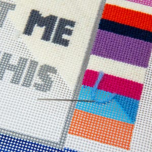 May include: A close-up of a needle and thread being used to stitch a colorful striped pattern on a white canvas. The text "LET ME DO THIS" is visible in the background.