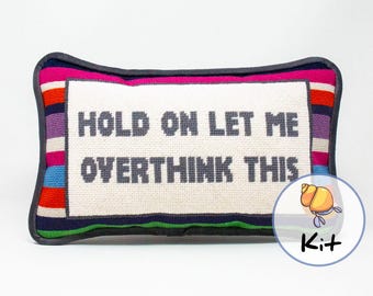 May include: A needlepoint pillow kit featuring a colourful striped border and the text "HOLD ON LET ME OVERTHINK THIS".