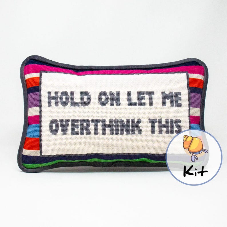 May include: A needlepoint pillow kit featuring a colorful striped border and the text "HOLD ON LET ME OVERTHINK THIS".