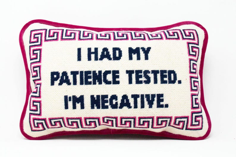May include: A white pillow with a pink border and a blue Greek key design. The pillow has the text "I had my patience tested. I'm negative." embroidered on it.