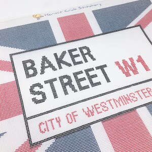 May include: A white canvas with a black frame and the text "BAKER STREET W1 CITY OF WESTMINSTER" printed in black. The canvas is decorated with a red, white, and blue Union Jack pattern.