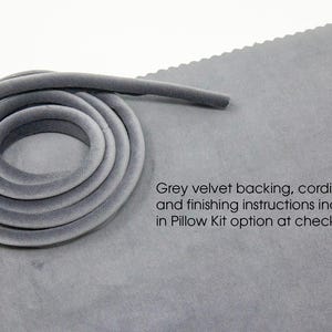 May include: Gray velvet cording for upholstery projects. The cording is rolled up on a gray fabric surface. The text "Grey velvet backing, cording, and finishing instructions included in Pillow Kit option at checkout." is printed on the fabric.