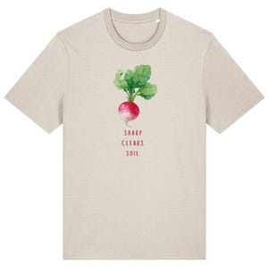 Könnte beinhalten: Beiges T-Shirt mit einer Illustration einer Radieschen und dem Text "SHARP CLEARS SOIL". Das Radieschen wird mit einer roten Knolle und grünen Blättern dargestellt. Das T-Shirt hat einen Rundhalsausschnitt und kurze Ärmel.