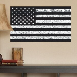 May include: A black and white distressed American flag wall decal. The flag is a simple design with white stars on a black field and white stripes on a black background.