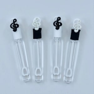 May include: Four clear plastic bubble wands with black and white treble clef shaped tops. The wands have a white bubble wand attached to the bottom.