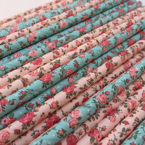 Peut inclure: Un lot de pailles en papier rose et turquoise avec un motif floral. Les pailles sont disposées en quinconce, les pailles roses au-dessus des pailles turquoise.