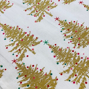 May include: White fabric with a gold glitter Christmas tree pattern. The trees are decorated with red and green glitter ornaments.
