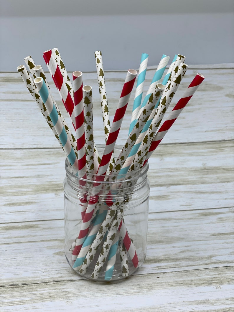 May include: A glass jar filled with red and blue striped paper straws with a gold tree pattern. The straws are arranged in a criss-cross pattern.