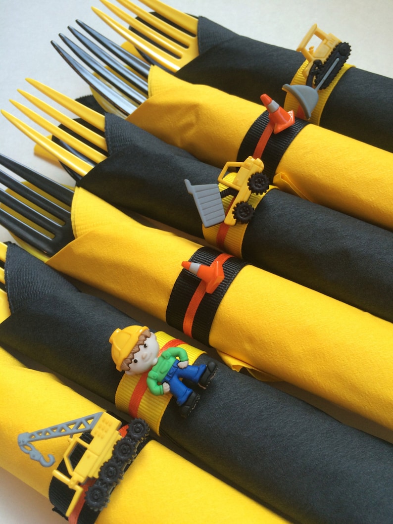 May include: Yellow and black construction themed napkin rings with a variety of construction vehicles and a construction worker figurine.