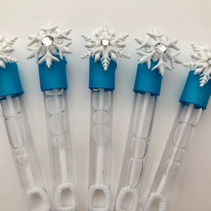 May include: Six clear plastic bubble wands with blue and white snowflake toppers. The wands are filled with bubble solution.