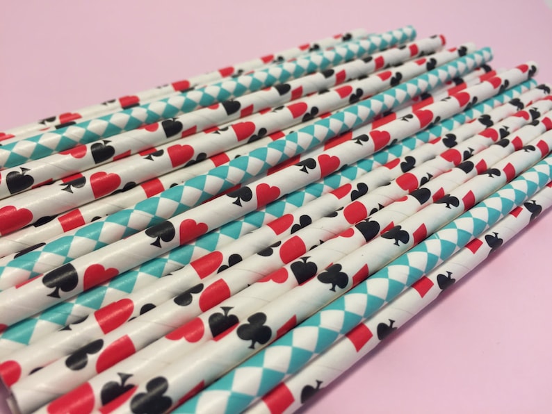 May include: A bundle of white paper straws with a blue and white diamond pattern and red and black playing card symbols.