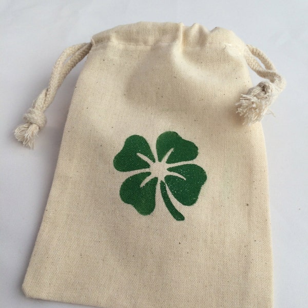May include: A small, white cotton drawstring bag with a green four-leaf clover design.