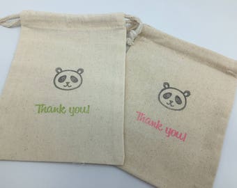 May include: Two small, beige fabric drawstring bags with panda bear illustrations and the text "Thank you!" printed in green and pink.