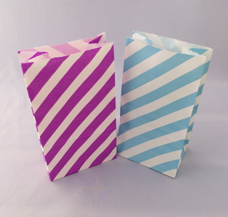 K&ouml;nnte beinhalten: Zwei gestreifte Papiert&uuml;ten, eine lila und wei&szlig;, die andere blau und wei&szlig;.