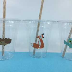 May include: Three clear plastic cups with brown paper straws. Each cup has a different woodland animal sticker: a hedgehog, a fox, and an owl.