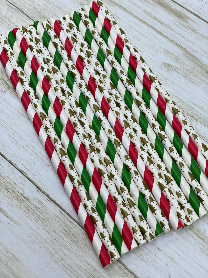 May include: A bundle of red and green striped paper straws with a white background and a gold Christmas tree pattern.