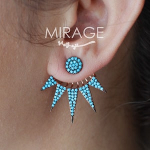 May include: A pair of turquoise and silver earrings with a starburst design. The earrings are made of small turquoise stones set in silver.