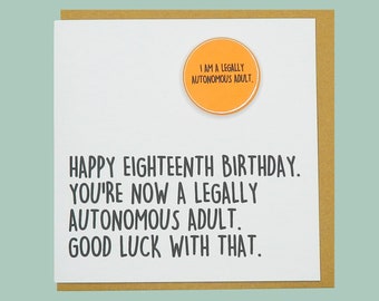 May include: A white card with a brown envelope. The card has black text that reads "Happy Eighteenth Birthday. You're now a legally autonomous adult. Good luck with that." There is a small orange circle with the text "I am a legally autonomous adult." on the card.
