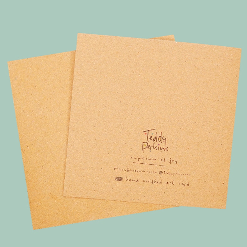 May include: A brown card with the text "Teddy Perkins, emporium of joy" and "hand crafted art cards" printed on it.