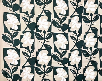 May include: A fabric with a repeating pattern of white floral shapes and dark green leaves and stems on a tan background. The floral shapes are enclosed in dark green squares. The fabric has a modern, botanical design.