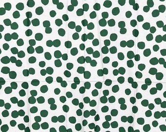 May include: White fabric featuring a repeating pattern of dark green polka dots. The dots are clustered and of varying sizes, giving a textured look. The fabric is folded, with visible creases.