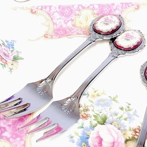 Pu&ograve; includere: Tre forchette d'argento con manici decorati con motivi floreali in tonalit&agrave; di rosso, bianco e oro. I manici sono sormontati da medaglioni ovali in porcellana con motivi floreali.