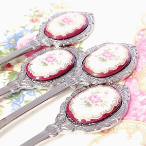 Pu&ograve; includere: Set di tre cucchiaini d'argento con manici decorati e disegni floreali rossi e bianchi sulla parte superiore di ogni manico.