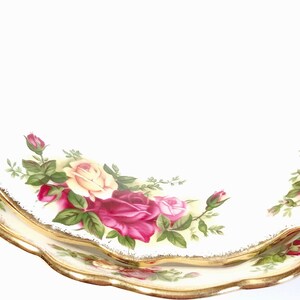 May include: Two white ceramic plates with a gold rim and a floral design featuring red, yellow, and green roses. The plates are stacked on top of each other.