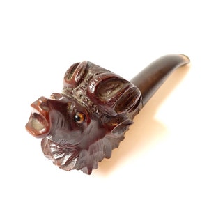 Puede incluir: Una pipa de madera tallada en forma de cabeza de jabal&iacute;. La pipa es marr&oacute;n y tiene una talla detallada de la cara del jabal&iacute;, incluidos sus ojos, hocico y colmillos. La pipa mide aproximadamente 15 cm de largo.