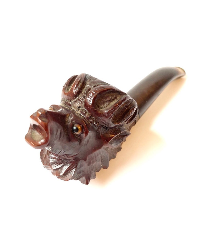 Puede incluir: Una pipa de madera tallada en forma de cabeza de jabal&iacute;. La pipa es marr&oacute;n y tiene una talla detallada de la cara del jabal&iacute;, incluidos sus ojos, hocico y colmillos. La pipa mide aproximadamente 15 cm de largo.