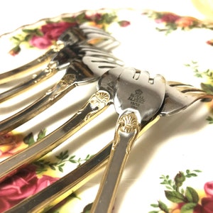 May include: Set of five silver forks with gold accents. The forks have a decorative design and are engraved with "Royal Albert 1810 1842".