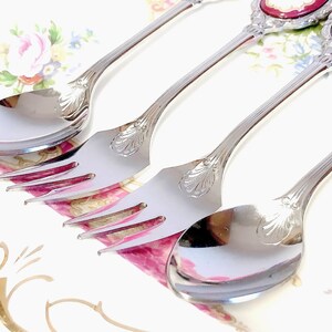 Pu&ograve; includere: Tre cucchiai d'argento con manici decorati e un motivo floreale. I cucchiai sono su uno sfondo bianco con un motivo floreale.