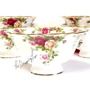 May include: Set of four white porcelain bowls with a floral pattern featuring pink, red, and yellow roses. The bowls have a scalloped edge and a gold trim.