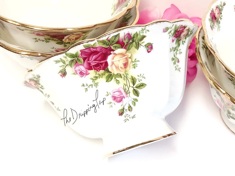 May include: A set of three white ceramic bowls with a gold rim and a floral pattern featuring red, pink, and yellow roses. The bowls are decorated with a green vine pattern and the text "the Dripping Tap".