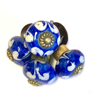 May include: Four blue and white ceramic cabinet knobs with gold accents. The knobs have a floral design.