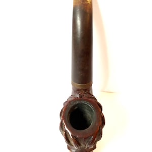 Puede incluir: Una pipa de madera marr&oacute;n con un dise&ntilde;o de cabeza de animal tallado. La pipa tiene una cazoleta negra y una boquilla marr&oacute;n.