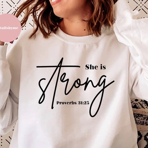 May include: White sweatshirt with black text that reads "She is strong Proverbs 31:25".