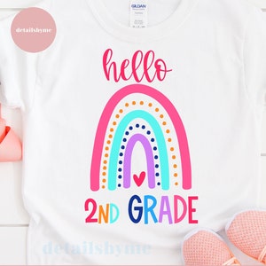 Puede incluir: Una camiseta blanca con un diseño de arcoíris y el texto "hello 2nd grade".