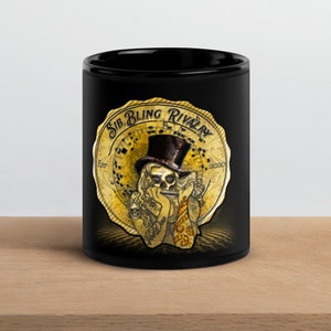 Puede incluir: Taza de cerámica negra con un emblema dorado que representa una calavera con sombrero de copa y un cigarrillo. El emblema dice "Sib. Bling Rivalry". La taza está sobre una superficie de madera.
