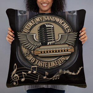May include: Black cushion with a musical theme. The cushion features a vintage microphone, harmonica, and wings design with the text "I LIKE MY SANDWICHES TO TASTE LIKE TIN". Musical notes are at the bottom.