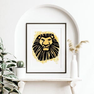 May include: A framed art print featuring a stylized lion's head. The lion is depicted in black with a yellow watercolor wash background. The artwork is displayed on a white shelf with a plant and vase.