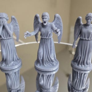 May include: A white ceramic mug with a black handle and the text "But First, Coffee" in a bold, black font. The mug is set against a blurred background, suggesting a cosy setting.