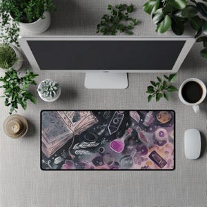 May include: A rectangular mousepad with a fantasy-themed design featuring an open book, potion bottles, and crystals. The color palette includes purple, pink, and black. The mousepad is on a gray surface, surrounded by plants, a computer monitor, a coffee cup, and a mouse.