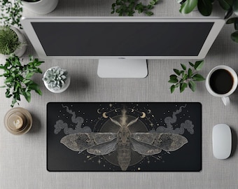 Op de afbeelding: Zwart rechthoekig muismat met een gedetailleerde illustratie van een mot, omringd door maan, sterren en rookachtige patronen. Het ontwerp staat op een grijze ondergrond, samen met een computermonitor, koffiekopje en muis.