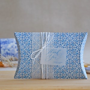 May include: Blue and white patterned pillow box with a white ribbon and a thank you tag that says "Thank You" with the names "Sarah & John" and the date "21.10.2023".